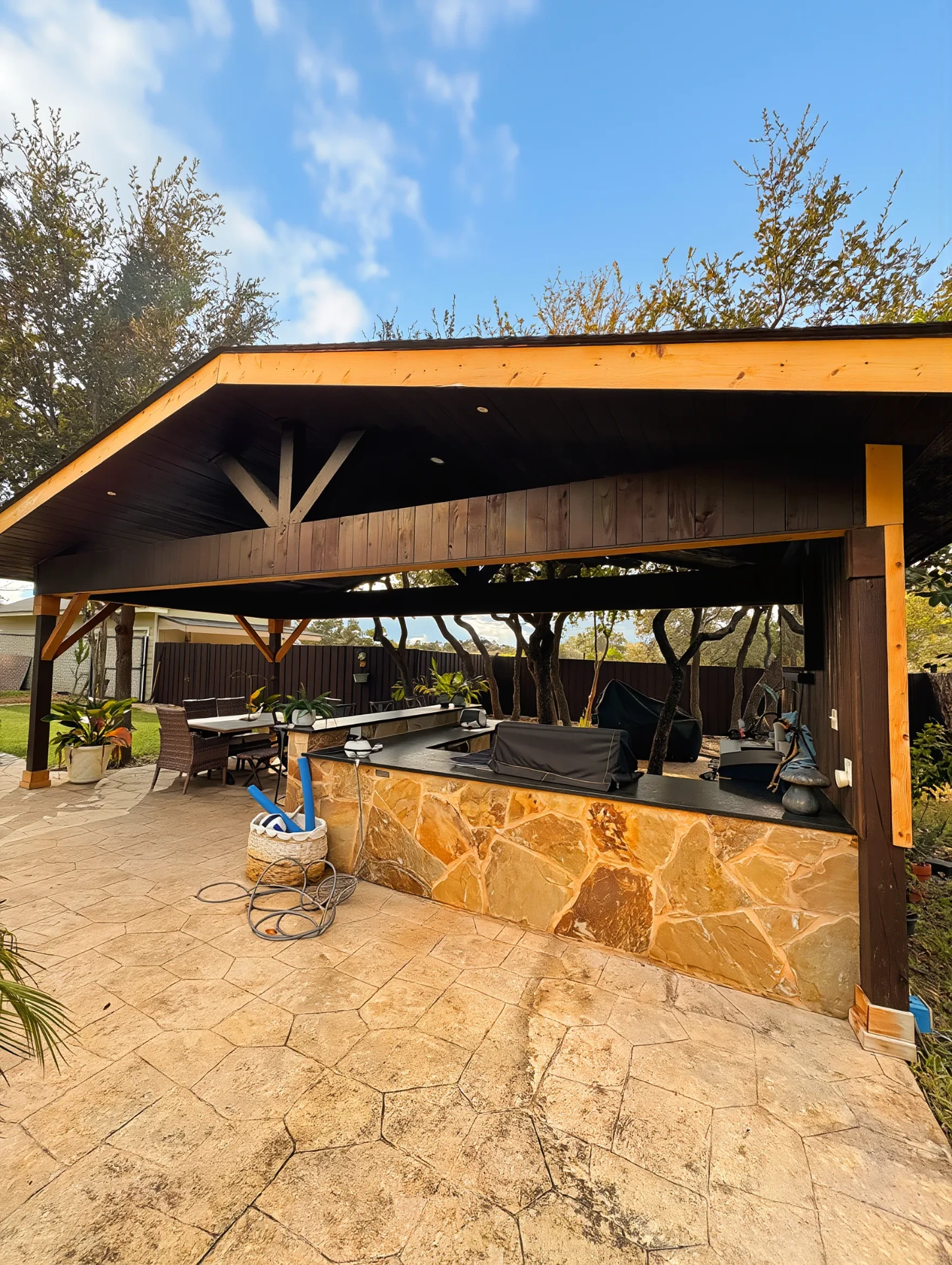Cedar pavilion with stone bar over stamped concrete patio