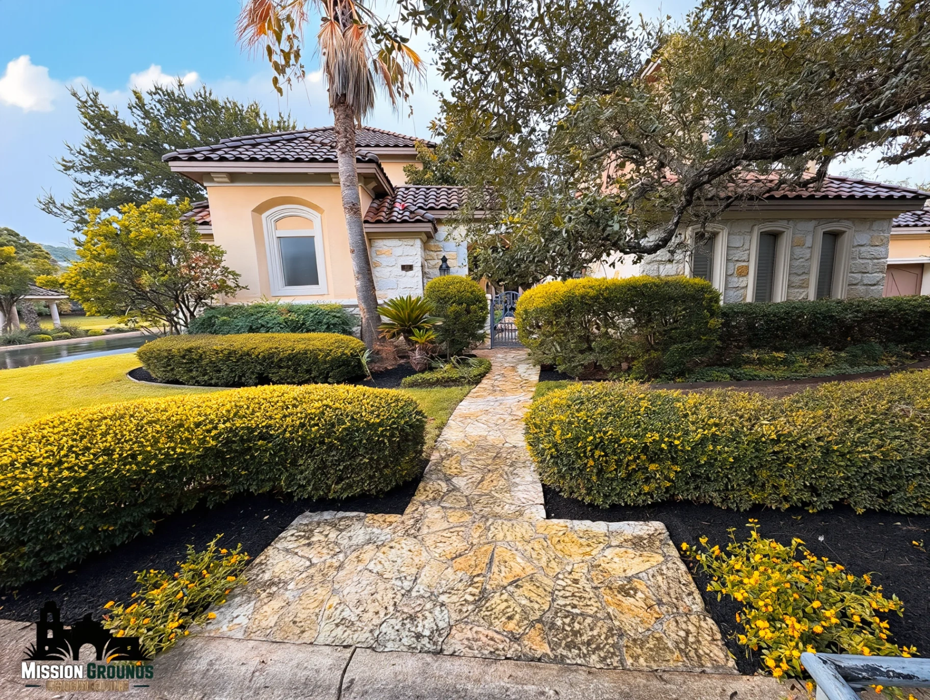 Mediterranean stucco estate with flagstone walk and clipped hedges