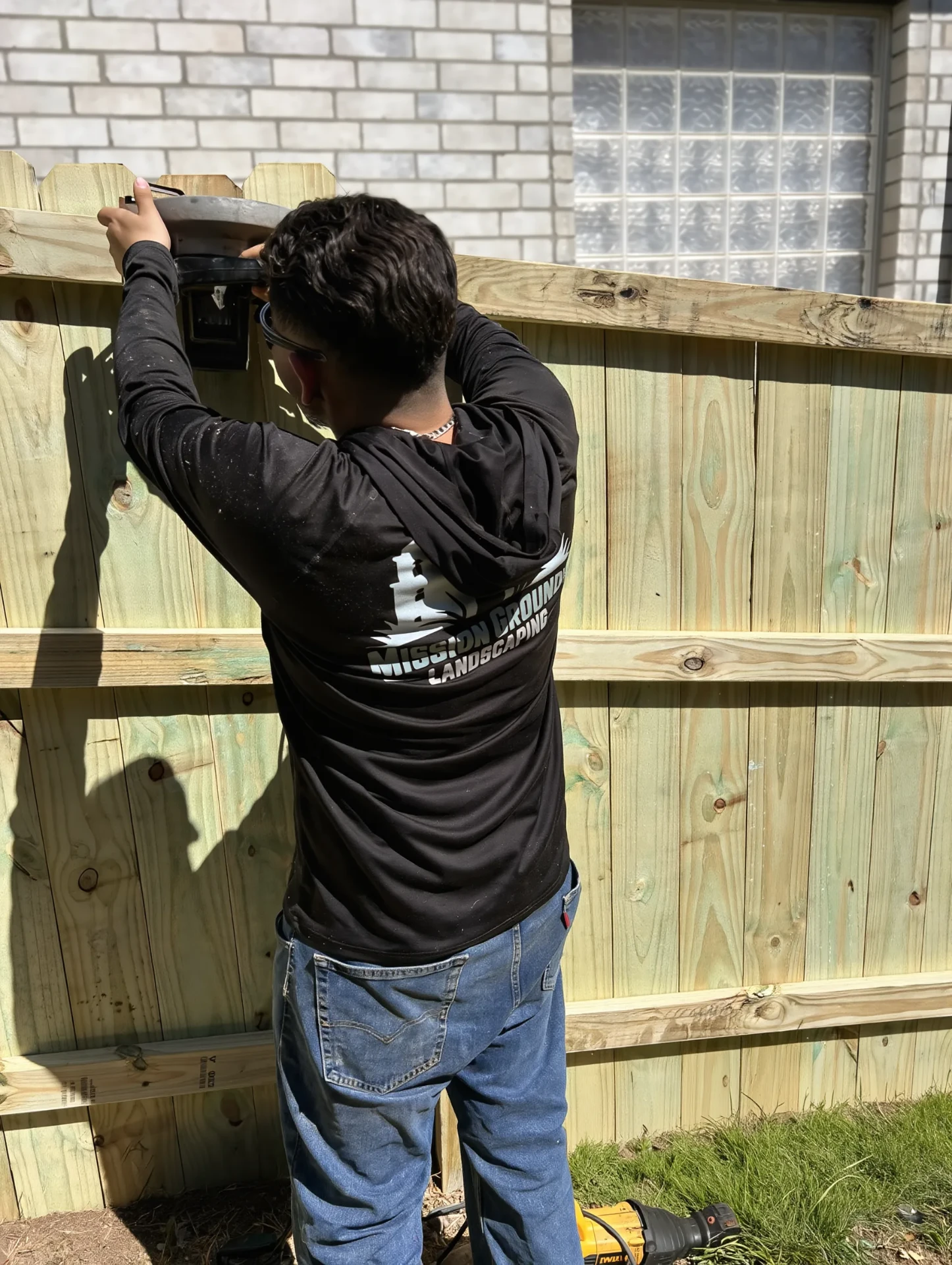 Mission Grounds crew member installing cedar privacy fence