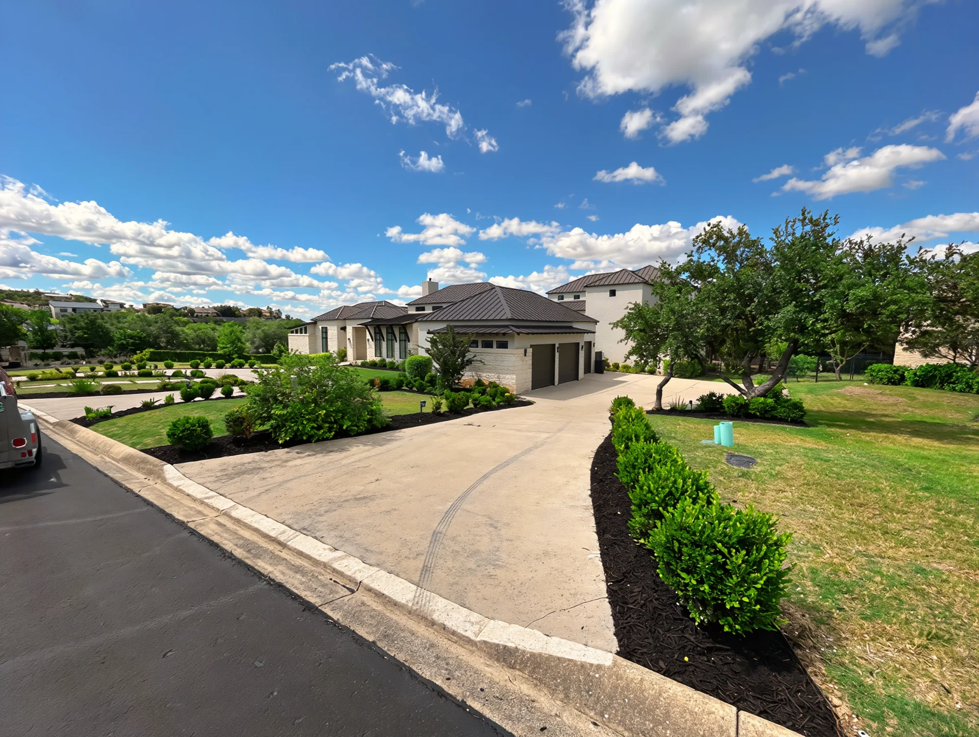 White limestone ranch home with manicured driveway plantings