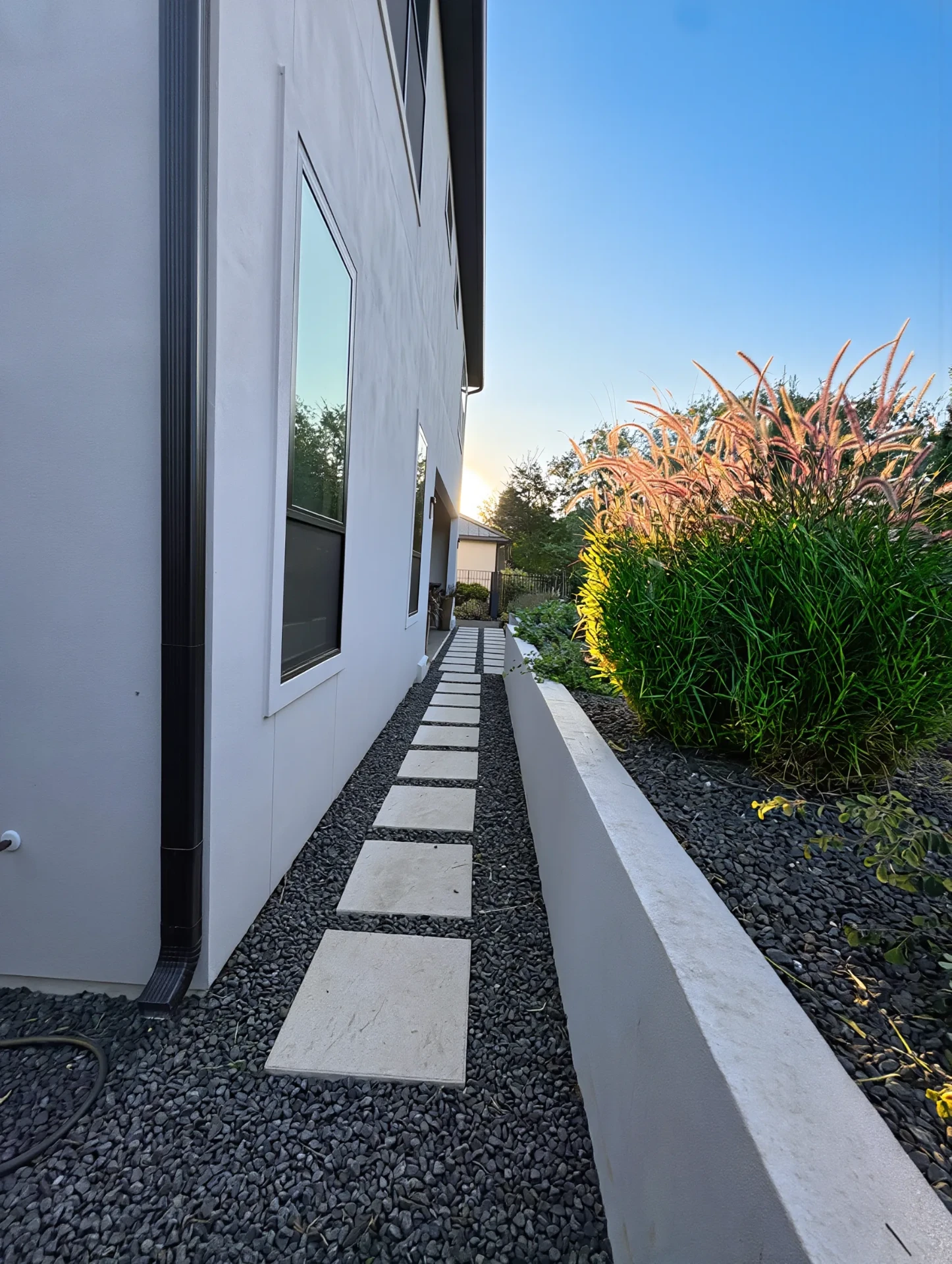 Side-yard stepping stones in white gravel beside stucco home